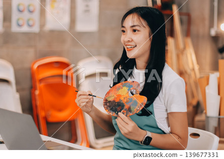 Female artist wears black hat posing near picture indoor the studio Female artist wears black hat posing near picture indoor the studio 139677331