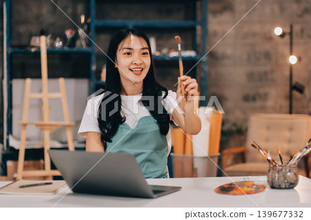 Female artist wears black hat posing near picture indoor the studio Female artist wears black hat posing near picture indoor the studio 139677332