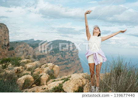 Joyful woman enjoying freedom and nature on a cliffside adventure 139677440