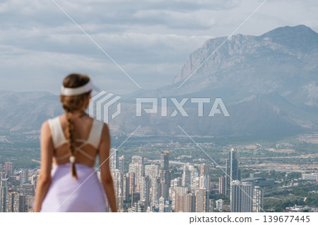 Woman in sportswear overlooking urban skyline and mountain landscape Woman in sportswear overlooking urban skyline and mountain landscape 139677445
