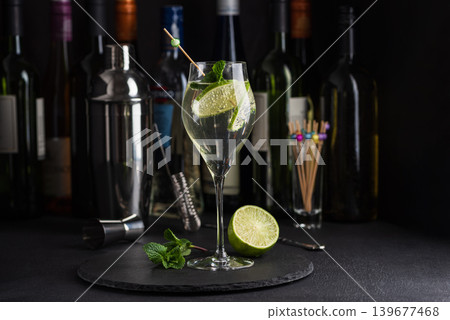 Elegant cocktail Martini Royale garnished with lime slices and fresh mint leaves against a refined bar background 139677468