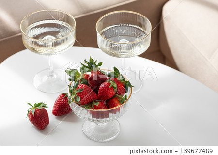 Champagne Glasses with Strawberries on White Table into Cozy Living Room Champagne Glasses with Strawberries on White Table into Cozy Living Room 139677489