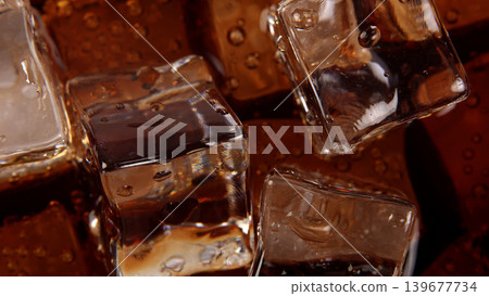Cola with Ice. Close up of the ice cubes in cola water. Texture of carbonate drink with bubbles in glass. Cola soda and ice splashing fizzing or floating up to top of surface. Cold drink background. Cola with Ice. Close up of the ice cubes in cola water. Texture of carbonate drink with bubbles in glass. Cola soda and ice splashing fizzing or floating up to top of surface. Cold drink background. 139677734