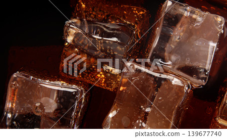 Cola with Ice. Close up of the ice cubes in cola water. Texture of carbonate drink with bubbles in glass. Cola soda and ice splashing fizzing or floating up to top of surface. Cold drink background. Cola with Ice. Close up of the ice cubes in cola water. Texture of carbonate drink with bubbles in glass. Cola soda and ice splashing fizzing or floating up to top of surface. Cold drink background. 139677740
