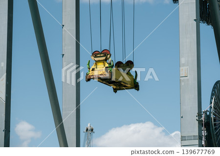 Industrial crane suspended against blue sky in port Industrial crane suspended against blue sky in port 139677769