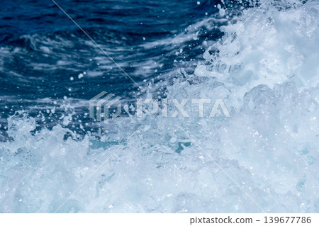 Dynamic ocean waves captured mid-splash with sparkling seafoam in blue waters 139677786
