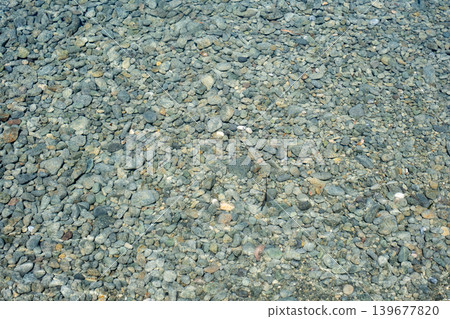 Crystal clear water over riverbed stones creating serene natural texture Crystal clear water over riverbed stones creating serene natural texture 139677820