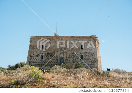 Historic coastal fortification under clear blue sky: ancient stone structure in natural landscape Historic coastal fortification under clear blue sky: ancient stone structure in natural landscape 139677854