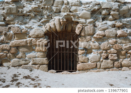 Ancient stone wall with iron gate in desert setting 139677901