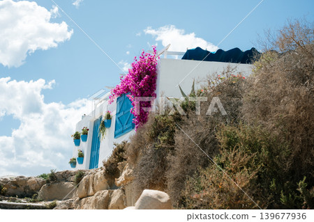 Greek island architecture with flowers and blue accents under clear sky 139677936