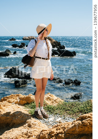Woman in sunglasses and summer outfit enjoying a rocky seaside Woman in sunglasses and summer outfit enjoying a rocky seaside 139677956