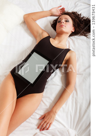 Sexy lazy girl lying with tablet touchpad on bed Sexy lazy girl lying with tablet touchpad on bed 139678431