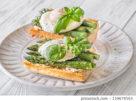 Gourmet Asparagus Bruschetta Topped With Perfectly Poached Eggs And Fresh Basil Leaves Gourmet Asparagus Bruschetta Topped With Perfectly Poached Eggs And Fresh Basil Leaves 139678563