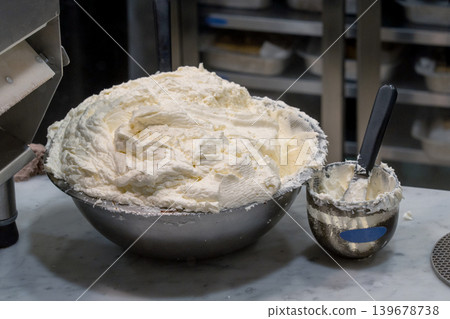Close-up of a large metal mixing bowl filled with a fluffy whipped cream or mascarpone cheese mixture, ready for desserts. Soft cream cheese. Close-up of a large metal mixing bowl filled with a fluffy whipped cream or mascarpone cheese mixture, ready for desserts. Soft cream cheese. 139678738