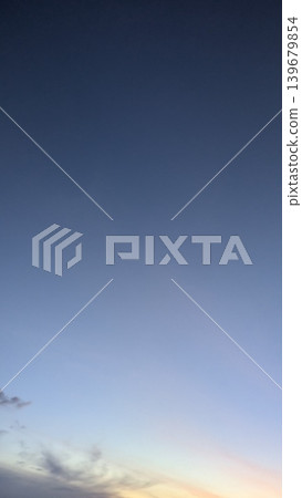 Vertical frame reveals a deep indigo sky fading into pale yellow light. Soft clouds gather near the bottom edge, creating a peaceful morning atmosphere. The view represents quiet transitions, natural 139679854