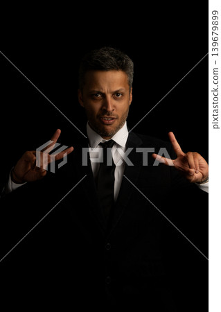 A man in a suit and tie is making a peace sign with his hands A man in a suit and tie is making a peace sign with his hands 139679899