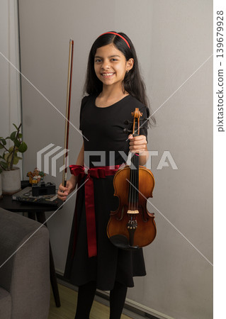 A young girl is holding a violin and smiling A young girl is holding a violin and smiling 139679928