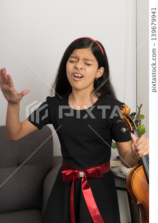 A young girl in a black dress is playing a violin A young girl in a black dress is playing a violin 139679941