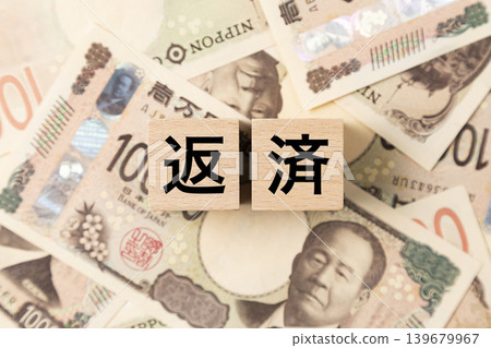 A block with the word "Repayment" written on it and lots of 10,000 yen bills. A block with the word "Repayment" written on it and lots of 10,000 yen bills. 139679967