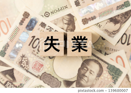 A block with the word "unemployment" written on it and lots of 10,000 yen bills. A block with the word "unemployment" written on it and lots of 10,000 yen bills. 139680007