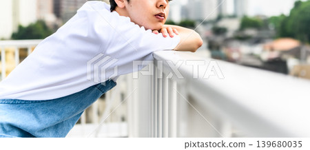 Close-up of a man leaning on the railing on a rooftop. Close-up of a man leaning on the railing on a rooftop. 139680035