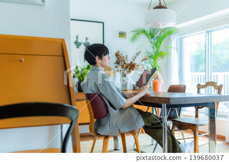 A man enjoying reading in a brightly lit room. A man enjoying reading in a brightly lit room. 139680037