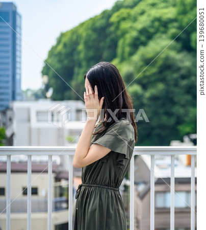 一位年輕女子，臉部被遮蓋，背景是綠色。 139680051