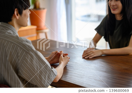 一男一女隔著桌子交談。 139680069