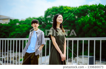 A young man and woman standing against a green background. 139680073