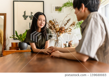 A man and a woman holding hands across a table A man and a woman holding hands across a table 139680083