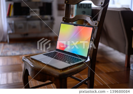 A laptop with colorful wallpaper placed on a chair A laptop with colorful wallpaper placed on a chair 139680084