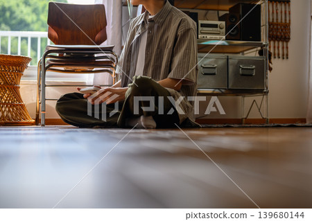 一個男人坐在地上看著他的智慧型手機 139680144