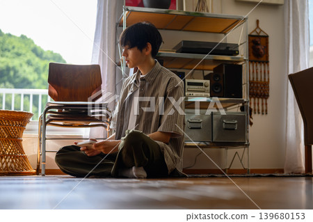 A young man sitting on the floor looking at his smartphone. A young man sitting on the floor looking at his smartphone. 139680153