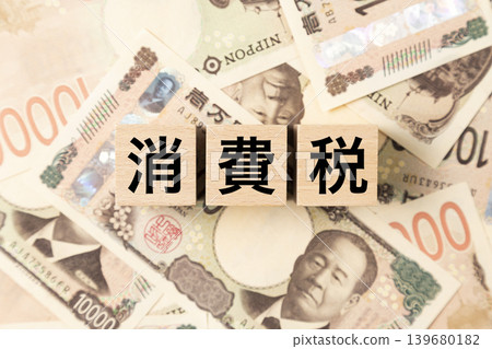 一塊寫著「消費稅」的鈔票和許多10,000日圓面額的鈔票。 一塊寫著「消費稅」的鈔票和許多10,000日圓面額的鈔票。 139680182