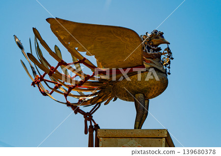 A phoenix decoration on a festival float against a blue sky. A phoenix decoration on a festival float against a blue sky. 139680378