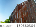 Rusty corrugated iron walls stretching out under the blue sky 139680384