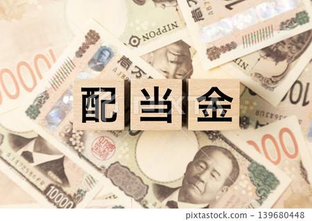 A block labeled "Dividends" and many 10,000 yen bills A block labeled "Dividends" and many 10,000 yen bills 139680448