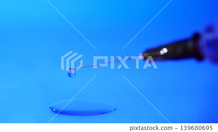 Close up of a syringe with a droplet of liquid on a blue surface in a clinical setting during laboratory work 139680695