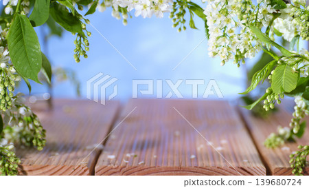 Flowers frame a wooden table with a blue sky background during spring in a garden setting 139680724