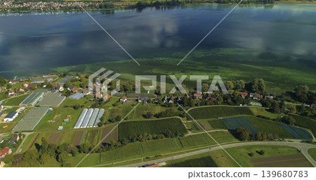 Vineyards and farms view near a lake with clear water and green plants in the landscape during daytime Vineyards and farms view near a lake with clear water and green plants in the landscape during daytime 139680783