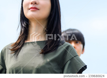 一張女人的臉和天空，她身後站著一個男人。 139680824