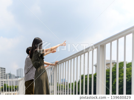 Two people pointing into the distance over the railing. Two people pointing into the distance over the railing. 139680829