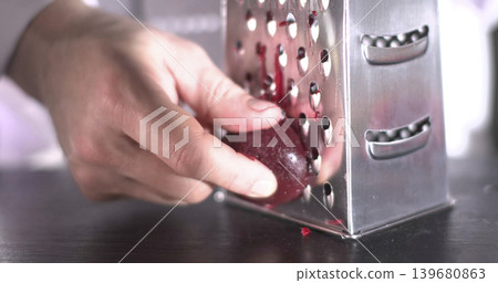 Grating a red fruit over a metal grater in a kitchen during the day for cooking Grating a red fruit over a metal grater in a kitchen during the day for cooking 139680863