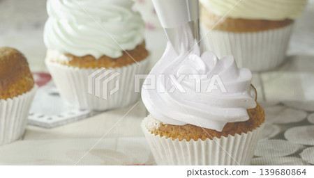 Decorating cupcakes with frosting in a kitchen on a sunny afternoon Decorating cupcakes with frosting in a kitchen on a sunny afternoon 139680864