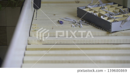 Woodworking process shows tools and screws on a workbench in a workshop during daylight hours Woodworking process shows tools and screws on a workbench in a workshop during daylight hours 139680869
