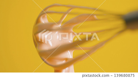 Whisk mixing creamy blend against bright yellow background in kitchen setting during baking session Whisk mixing creamy blend against bright yellow background in kitchen setting during baking session 139680875