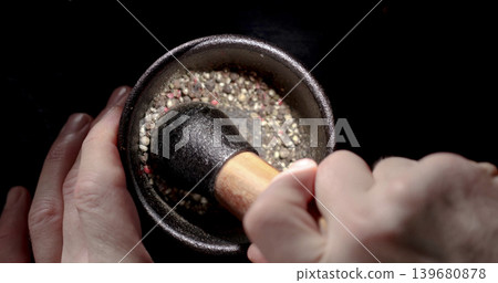 Grinding spices with a pestle in a mortar at a kitchen counter during daytime 139680878