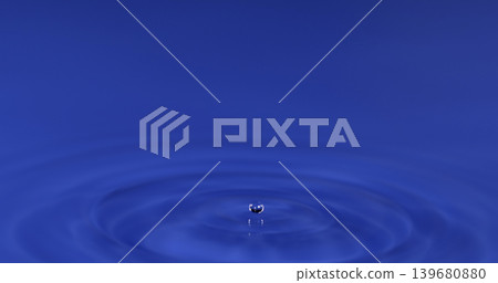 Water droplet causes ripples in blue surface during a drop event Water droplet causes ripples in blue surface during a drop event 139680880