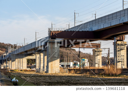 Modern railway infrastructure, the massive elevated tracks and concrete bridges of the Shinkansen, and tranquil rural scenery. Modern railway infrastructure, the massive elevated tracks and concrete bridges of the Shinkansen, and tranquil rural scenery. 139681118