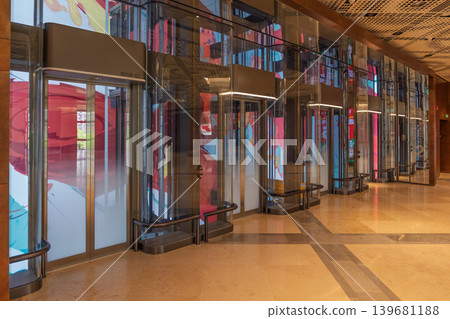 Glass elevators and colorful murals in the interior space of a shopping mall Glass elevators and colorful murals in the interior space of a shopping mall 139681188